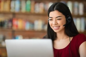 Remote Jobs. Asian Girl Call Center Operator With Headset And Laptop, Closeup